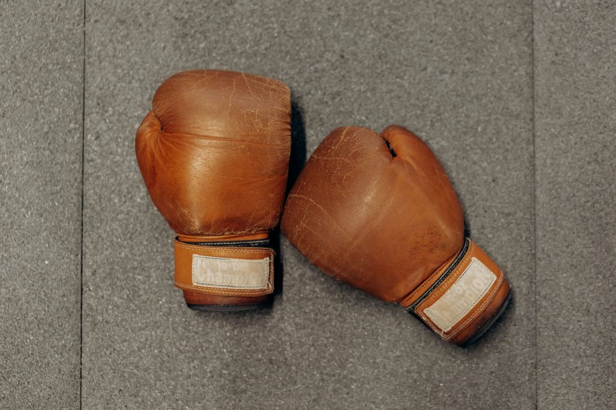 Brown leather boxing gloves on a textured gray gym surface