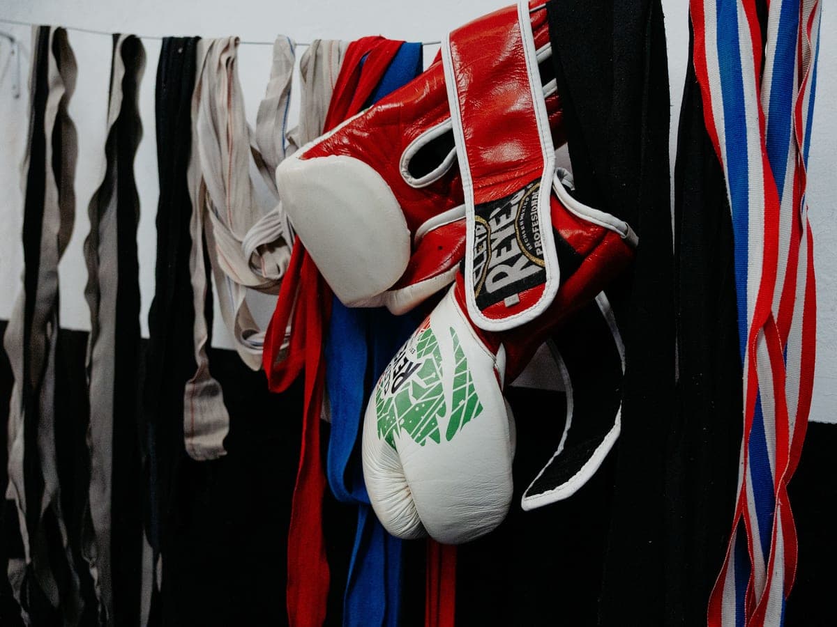 Red Cleto Reyes boxing gloves and hand wraps hanging in a gym
