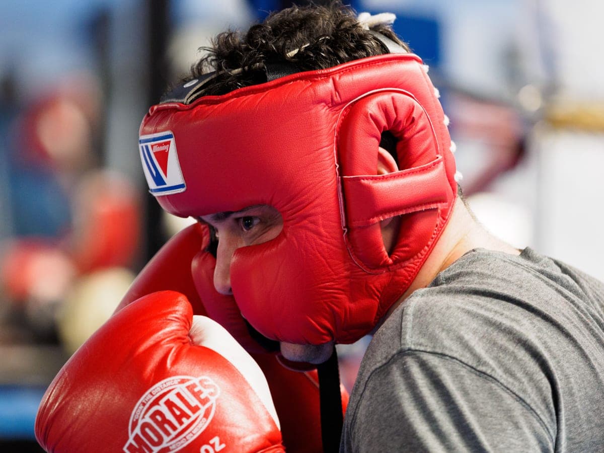 A boxer wearing red gloves and open-face headgear during indoor training