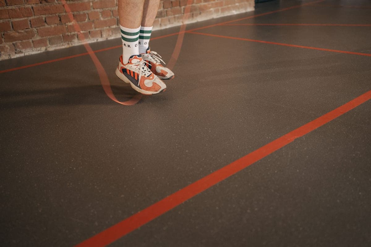 Feet in sneakers skipping rope on an indoor gym floor