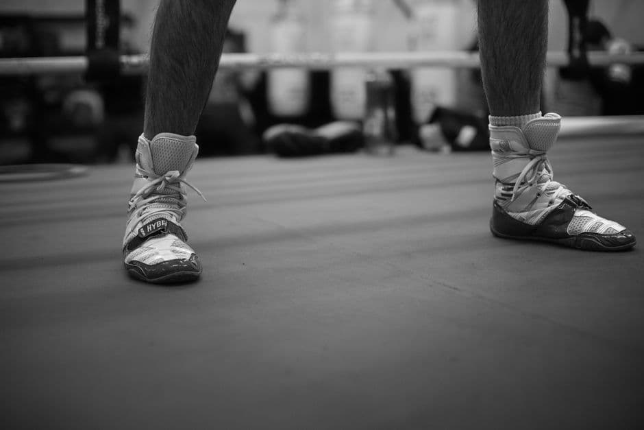 Boxing shoes laced up on a ring canvas in a gym