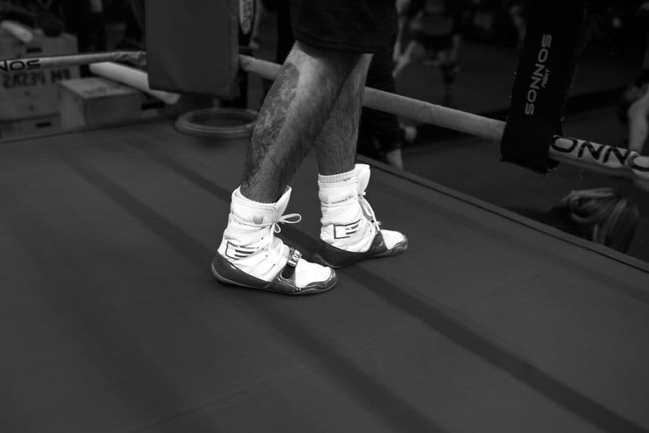 A boxer's feet on the canvas of a boxing ring, in black and white