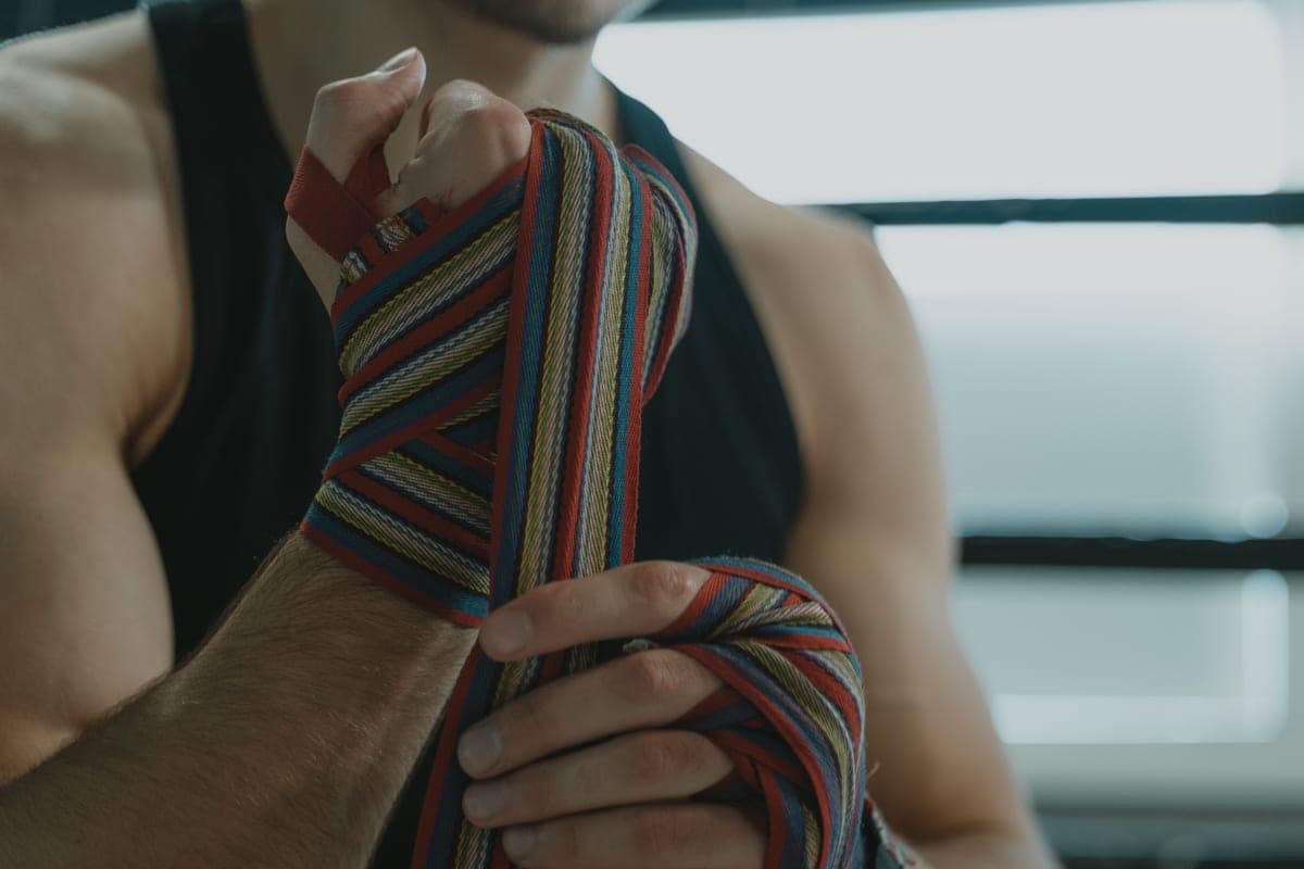 A man wrapping his hands with striped boxing hand wraps